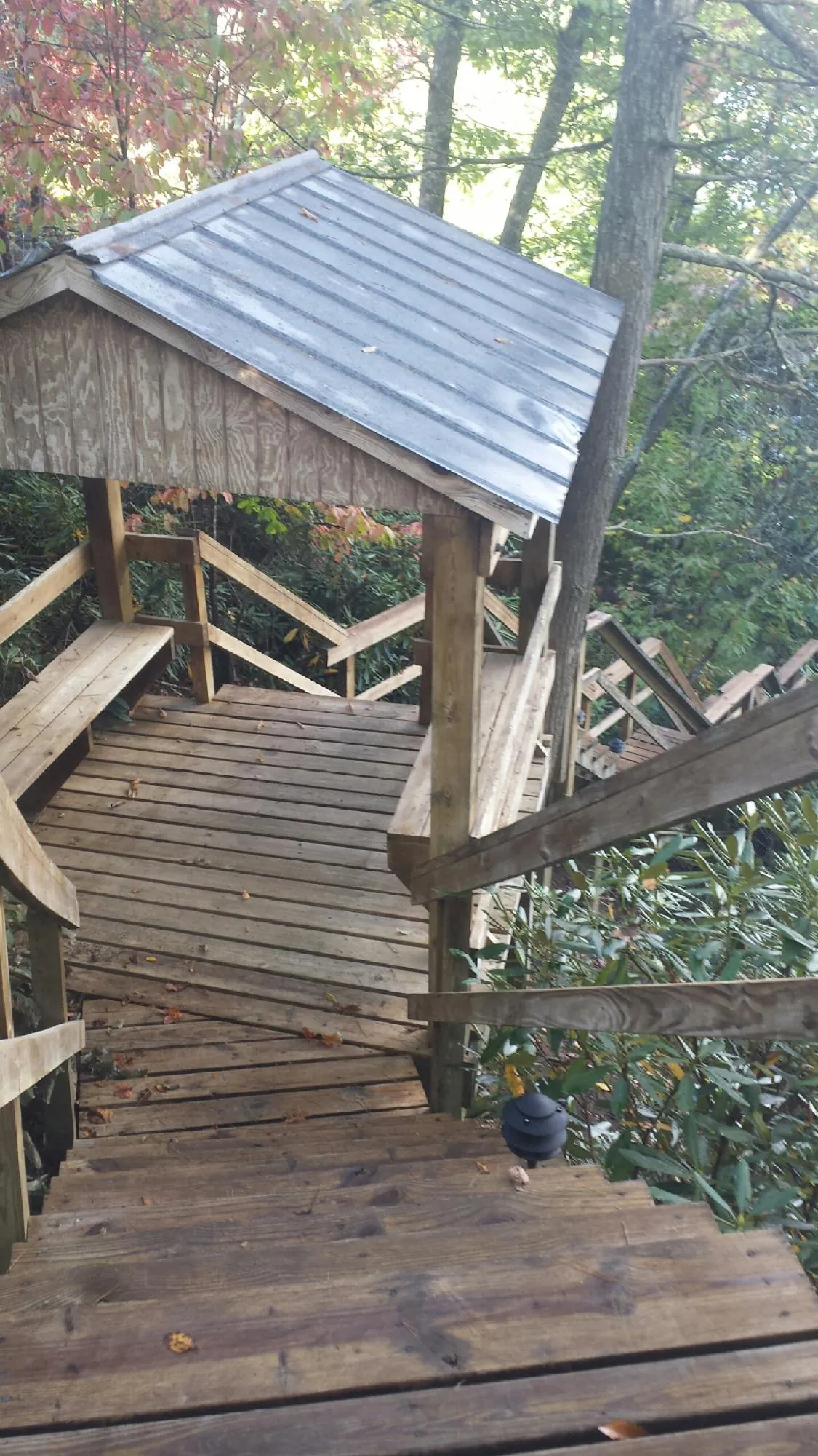 Metal roofed shelter over wooden steps on a wooded walkway — Skylight Repair & Installation work by our crew in Cutler